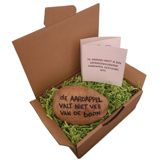 Een pakket met daarin een aardappel met daarop de tekst handgeschreven in zwarte inkt “de aardappel valt niet ver van de boom”.  Een wit zigzak boekje met de tekst “Ja, iemand heeft je een gepersonaliseerde aardappel gestuurd. WTF.” Verpakt in een hysterisch groen verpakkingsmateriaal.